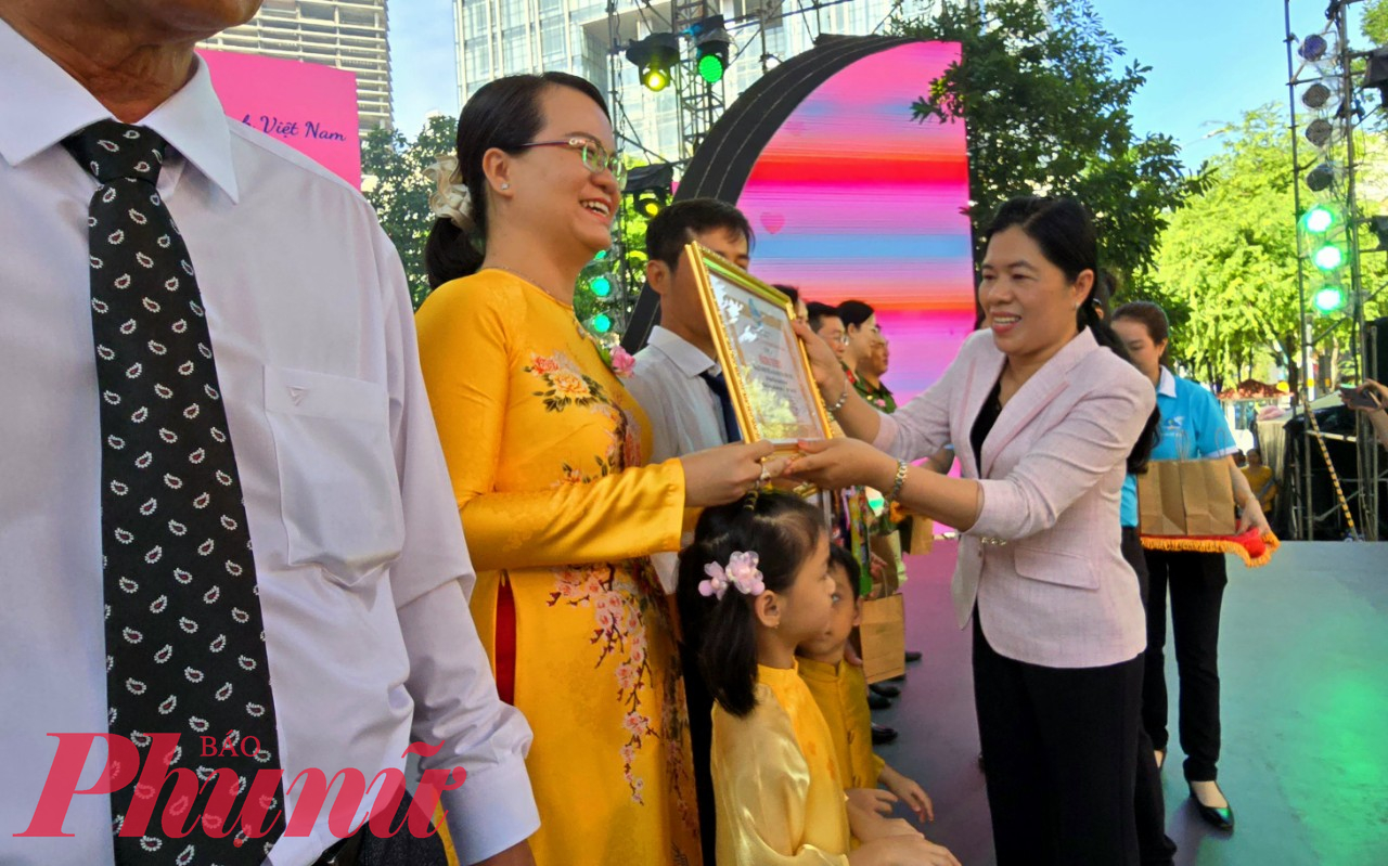 Bà Nguyễn Trần Phượng Trân - Chủ tịch Hội LHPN TPHCM - tặng Bằng khen cho các gia đình được tuyên dương tại sự kiện 