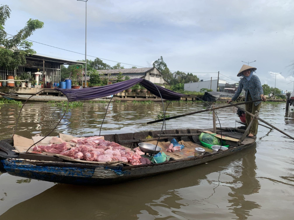 Một người phụ nữ chèo ghe từ con rạch ven sông Hậu để ra bán thịt heo cho những ghe thương hồ. Ở chợ nổi Long Xuyên, mọi việc mua bán trao đổi hàng hoá đều thông qua ghe thuyền.