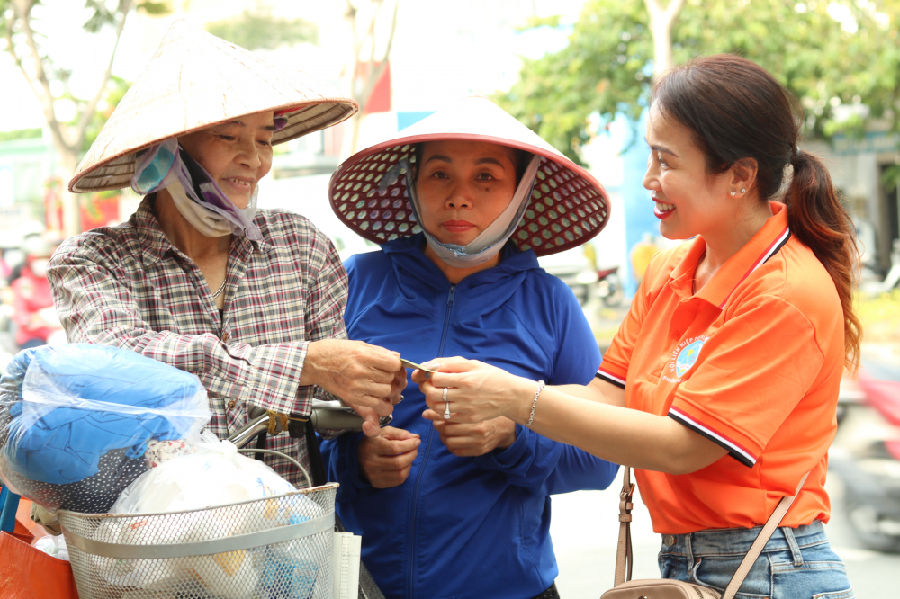 Trong ngày đầu mở cửa, chị Trần Thị Minh Thư (bìa pphải), ở khu phố 15, phường An Khánh tặng thêm cho mỗi bà con ghé cửa hàng 100.000 đồng tiền mặt. 