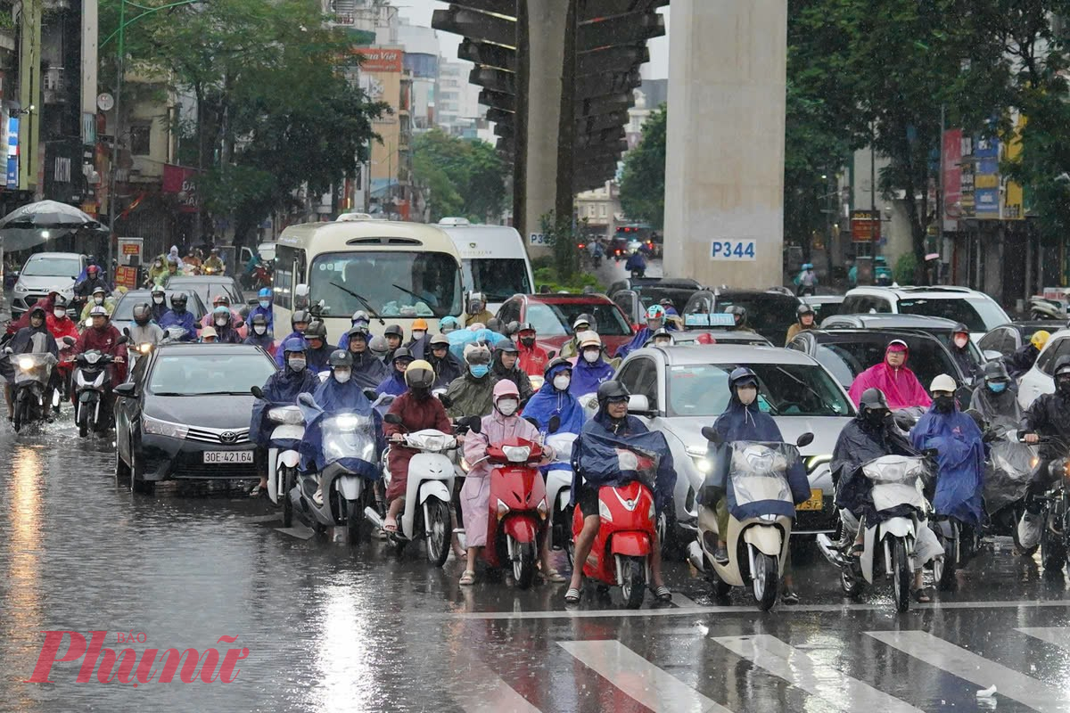 Giao thông ùn tắc cùng cơn mưa sáng sớm khiến người lao động càng thêm vất vả khi di chuyển.