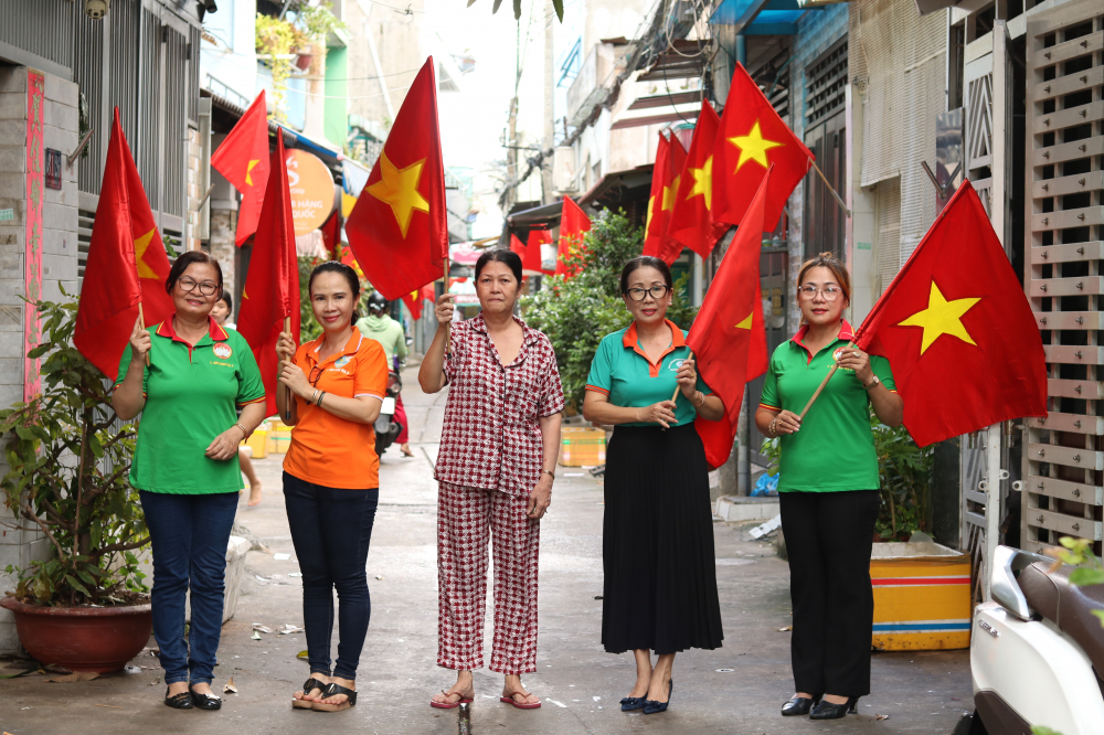 Bà Hồ Thị Bạch Tuyết (thứ hai, từ phải sang) - Bí thư Chi bộ kiêm Trưởng khu phố 32, phường Bình Hưng Hòa A - cho biết, khu phố 32 và 33 được tách ra từ khu phố 14 cũ, hiện có tổng cộng 1.050 hộ dân. Vào dịp kỷ niệm 30/4/2023, cán bộ khu phố đã cùng anh chị em các đoàn thể vận động 100% hộ dân tại 2 khu phố cùng đồng lòng thực hiện tuyến đường, tuyến hẻm cờ Tổ quốc. “Bà con chỉ góp kinh phí mua lá cờ đầu tiên. Khu phố chịu trách nhiệm bảo quản. Lá cờ nào phai màu, cũ, rách sẽ được thay mới để treo trong các dịp lễ lớn của đất nước. Những ngày qua, khi cờ được treo từ đầu tới cuối các con hẻm, rất nhiều khách có dịp chạy xe vô đây đều dừng lại đứng nhìn rất lâu vì xúc động” - bà Tuyết thông tin.