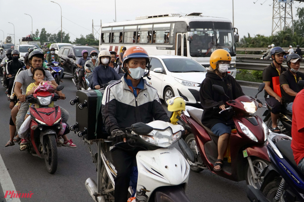 Trên những chiếc xe máy, nhiều người chở theo gia đình hoặc một số hành lý phía sau - Ảnh: Vũ Quyền