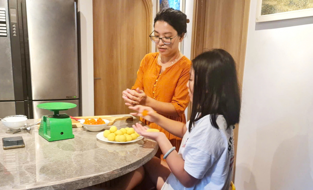 Chị Nguyễn Thanh Huyền - phóng viên Báo Phụ nữ TPHCM - hướng dẫn con làm những công việc hằng ngày để san sẻ việc nhà với cha mẹ - ẢNH: T.H.