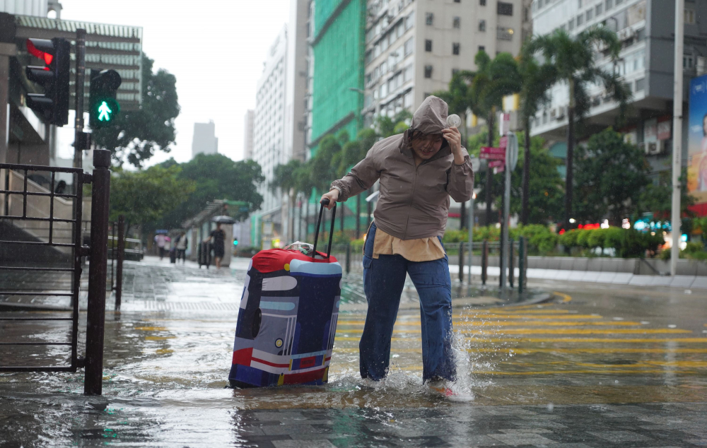 Một người phụ nữ băng qua đường ở quận Tsim Sha Tsui, Hồng Kông dưới trời mưa lớn ngày 6/9 - Ảnh: ADAM LAM/CHINA DAILY