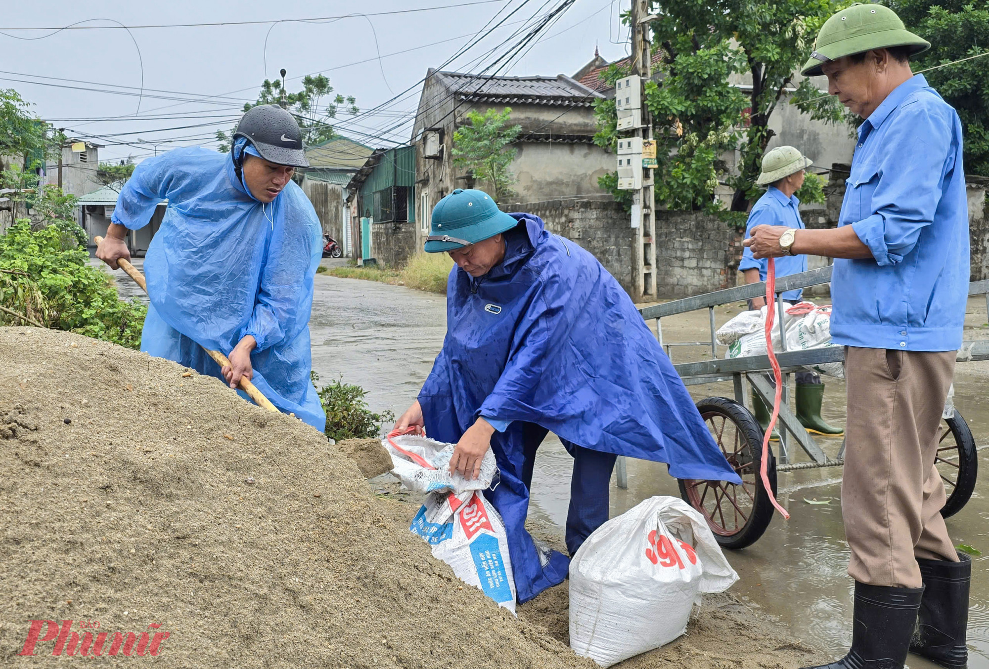 Người dân phường Nghi Thủy xúc cát để đưa lên mái nhà, mái tôn.