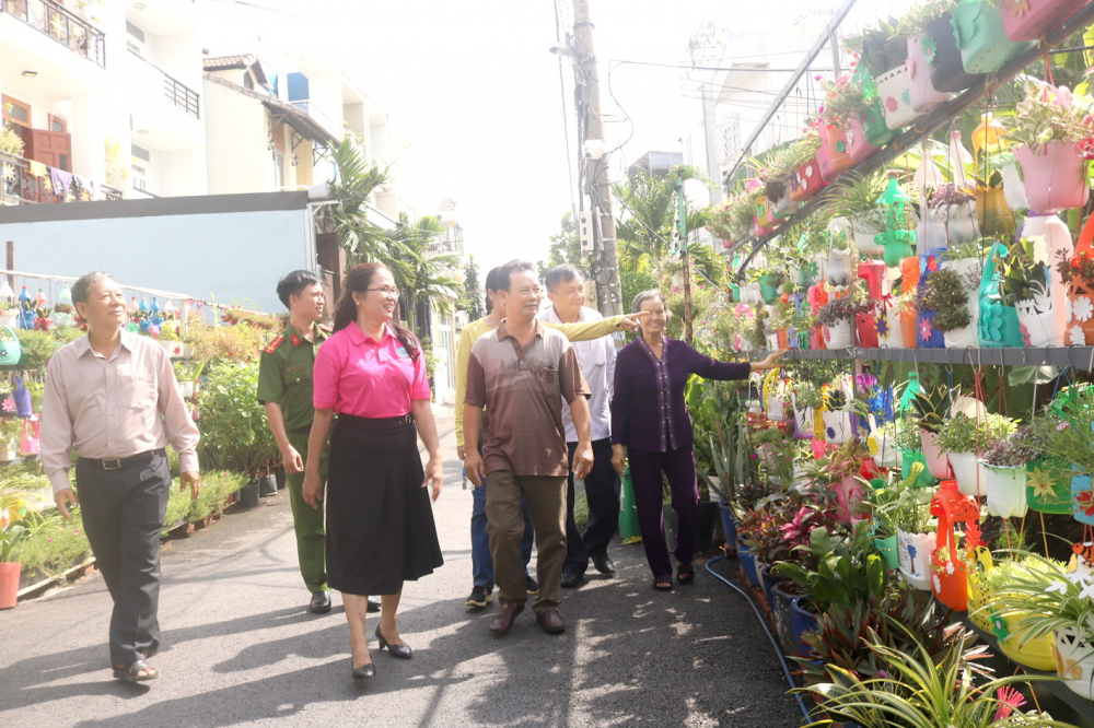 Cán bộ  địa phương và người dân cùng tham quan đường hoa từ rác thải tái chế tại hẻm 606/32 Quốc lộ 13