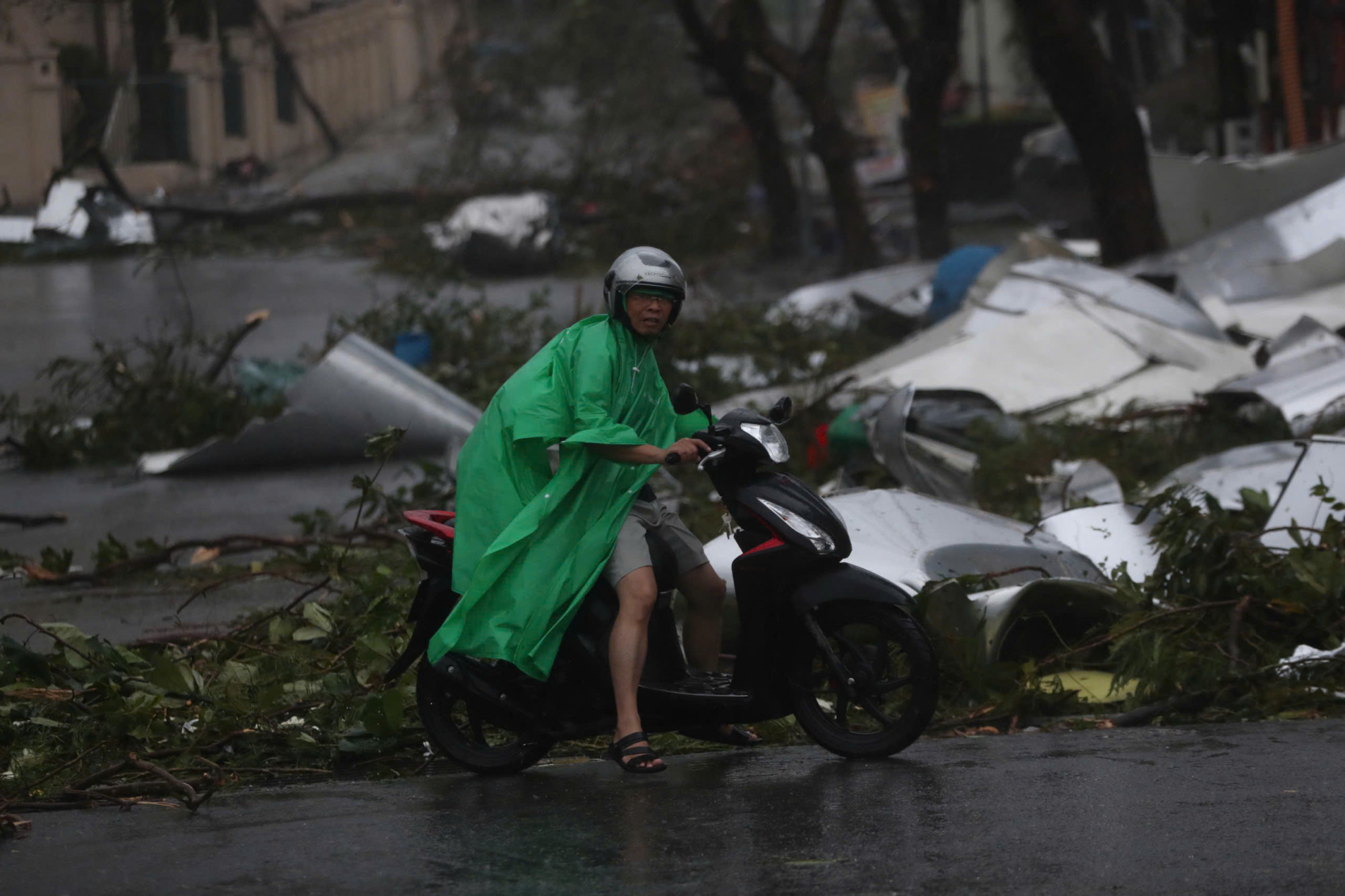 Một người dân Quảng Ninh di chuyển trên đường ngổn ngang vật liệu xây dựng bị gió cuốn tung - Ảnh: N.A