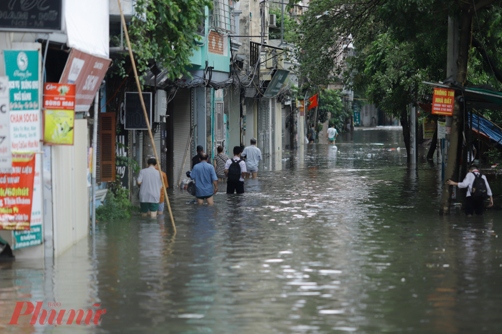 Người dân bì bõm lội nước ngập sâu nửa người để trở về nhà.