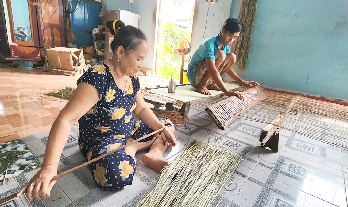 Bà Phạm Thị Kim Oanh cùng con trai bên khung dệt truyền thống