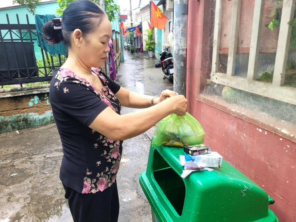 Bà Ngô Thị Rượi thường xuyên kiểm tra, phân loại rác tại thùng rác lớn để làm gương cho cả khu nhà trọ - ẢNH: THU LÊ