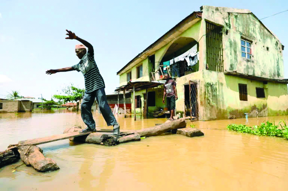 Một người đàn ông di chuyển qua dòng nước lũ ở bang Kogi, Nigeria, vào ngày 17/9/2018. Năm nay, dự kiến có khoảng 250.000 người ở Kogi phải di dời do lũ lụt - Ảnh: Afolabi Sotunde (Reuters)