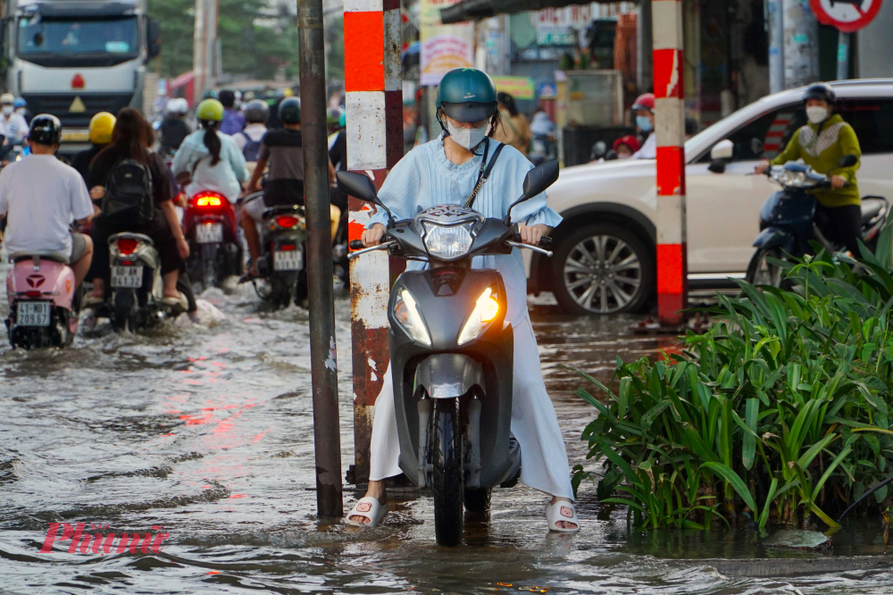 Một số người tìm cách đi lên vỉa hè để tránh chỗ ngập - Ảnh: Vũ Quyền