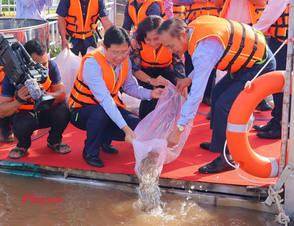 Đại biểu thả cá giống xuống sông Tiền - Ảnh Việt Tiến