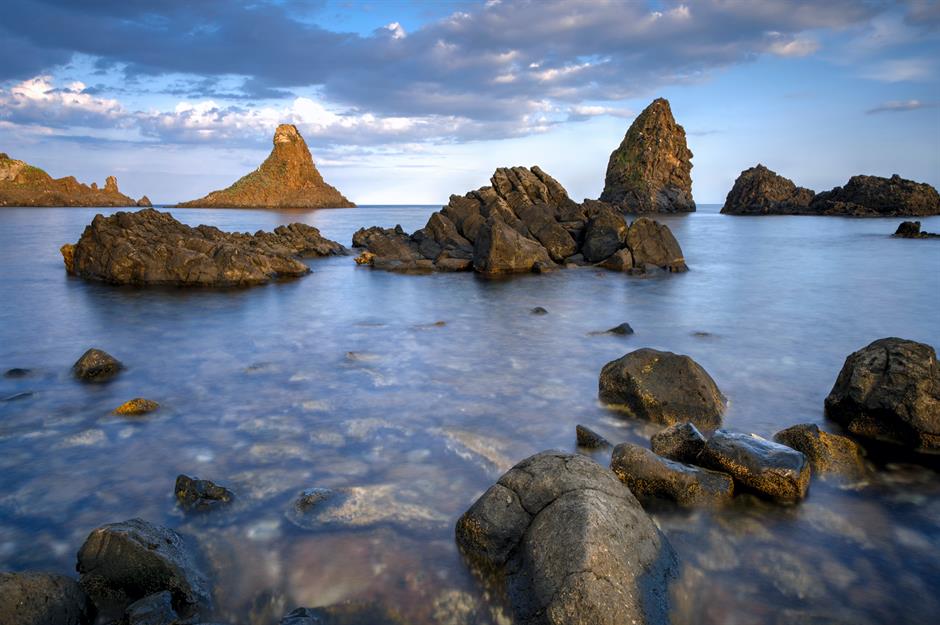 Quần đảo Cyclopean, Sicily, Ý Một địa điểm có thật khác liên quan đến The Odyssey của Homer là ba khối đá khổng lồ nhô ra biển ngoài khơi bờ biển phía đông của Sicily. Người ta nói rằng chúng là 'những đỉnh núi lớn' mà tên khổng lồ Polyphemus một mắt đã xé toạc từ một ngọn núi và ném vào Odysseus cùng thủy thủ đoàn của ông khi họ chạy trốn khỏi Đảo Cyclops trên con tàu của mình. Được người dân địa phương gọi là Quần đảo Cyclopean, những khối đá nổi bật này có thể được nhìn thấy ngay ngoài khơi từ ngôi làng ven biển Aci Trezza.