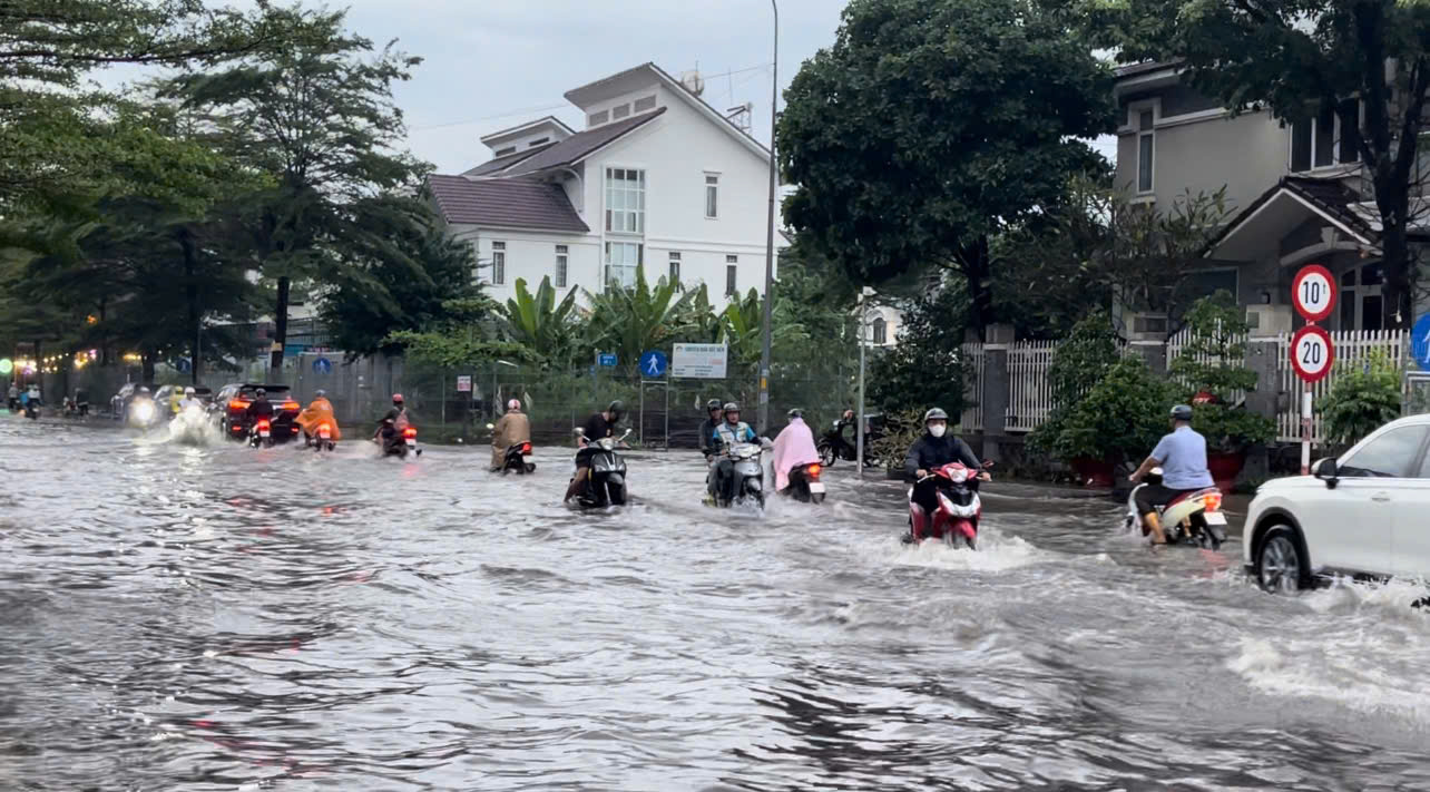 Đoạn đường phía sau trung tâm thương mại SC Vivo (Quận 7, TPHCM) ngập nặng, người dân chật vật vượt biển nước để né ổ gà. 