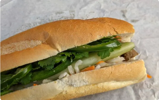 Bánh mì thịt ở đây rất ngon. Bánh  giòn tan được làm mới mỗi ngày kết hợp với các loại nhân như: chạo tôm, gà nướng sả, thịt heo quay làm ổ bánh trở nên đặc biệt. Phần lớn thực khách đều yêu thích bánh mì thịt truyền thống với nhân: pate, bơ, giăm bông, chả lụa cùng với rau, đồ chua. Ảnh: Zach Long