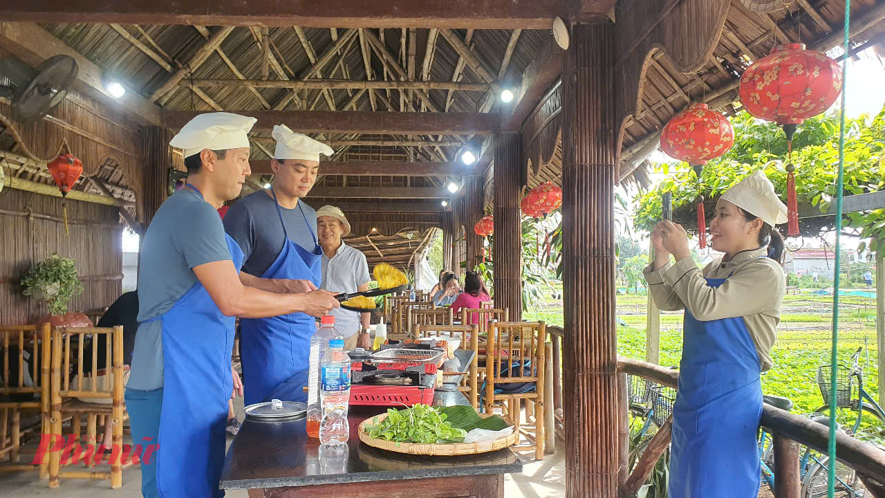 Khách du lịch trải nghiệm nấu ăn và ghi lại khoảnh khắc tại nhà hàng Tra Que Water Wheel, làng rau Trà Quế, Hội An