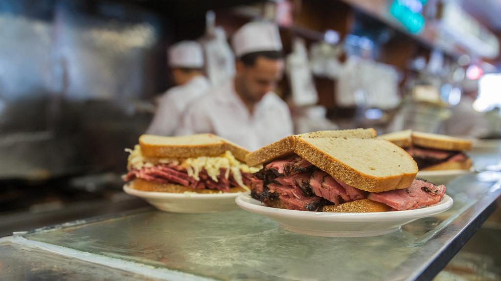 Cửa hàng đồ ăn nhẹ Katz, New York Ở New York, tôi luôn đến Katz's Delicatessen để thưởng thức món pastrami trên bánh mì lúa mạch đen – đó là toàn bộ trải nghiệm. Bạn xếp hàng dài này, nhưng nó di chuyển rất nhanh. Bạn lấy một tấm vé, boa cho anh chàng sau quầy, và trong khi anh ta đang làm bánh sandwich cho bạn, anh ta đưa cho bạn một lát pastrami để ăn nhẹ. Pastrami ấm, ngon ngọt và được nhồi cao giữa các lát bánh mì. Họ cho thêm một ít dưa chua vào bên cạnh – mọi thứ về nó đều có vẻ hào phóng.