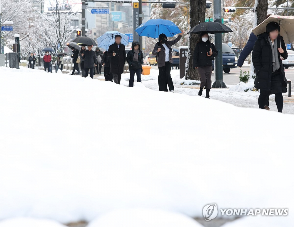 Mọi người đi bộ giữa tuyết rơi dày ở Seoul vào ngày 28/11/2024 - Ảnh: Yonhap