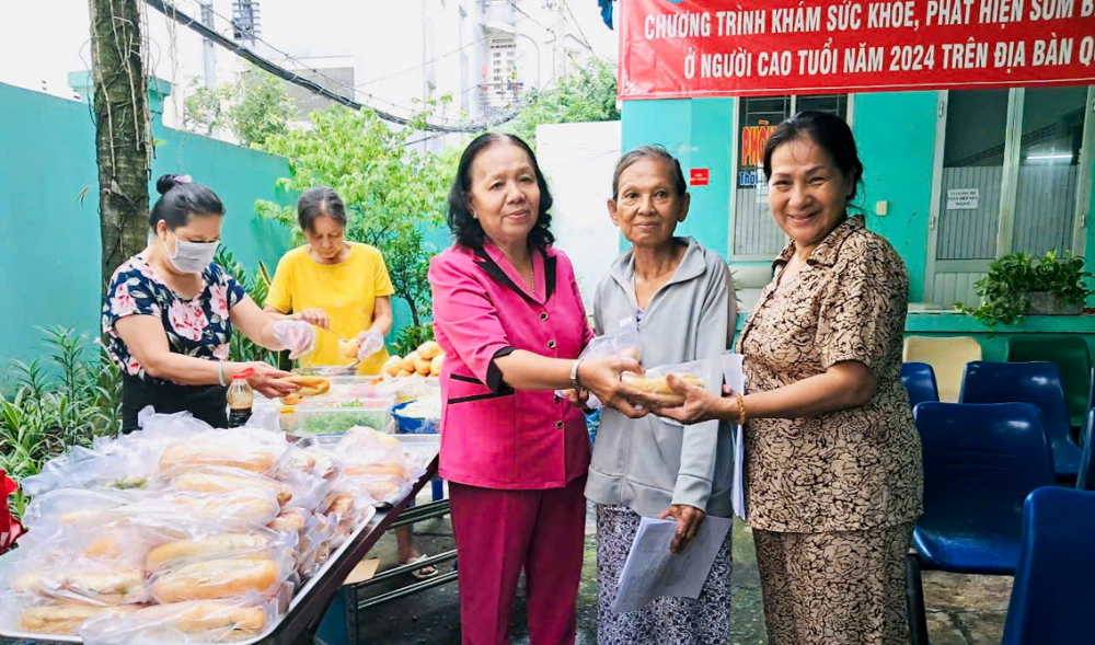 Bà Nguyễn Thị Kim Hoàng (thứ ba từ phải sang) trao tặng suất ăn cho những người khó khăn