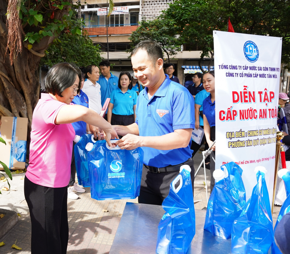 Người dân chung cư Nhiêu Lộc C nhận túi nước từ nhân viên Cấp nước Tân Hòa