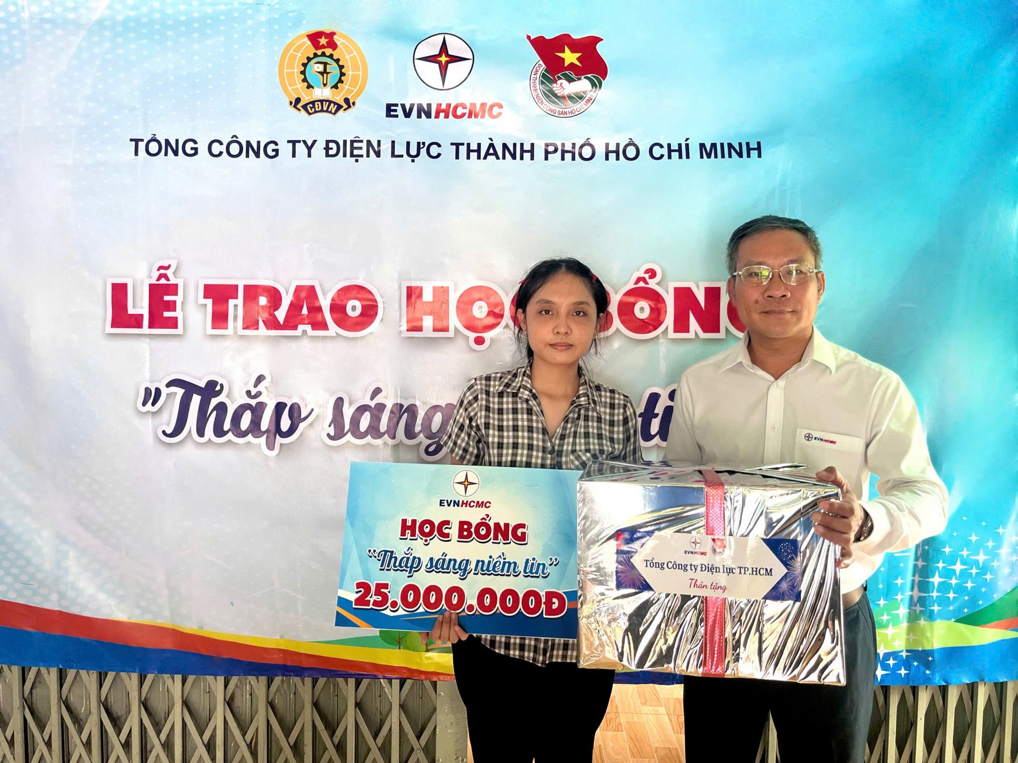 Ông Bùi Trung Kiên - Phó tổng giám đốc EVNHCMC trao quà và phần học bổng cho em Lê Ngọc Như Ý - Ảnh: EVNHCMC