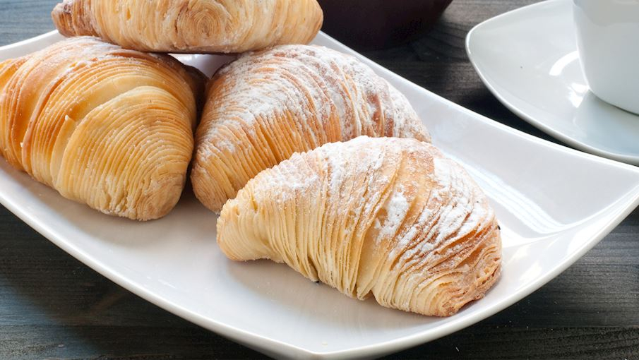 **Sfogliatella** là một loại bánh ngọt truyền thống nổi tiếng của Napoli, Ý. Bánh có hình vỏ sò đặc trưng với lớp vỏ mỏng, giòn rụm được làm từ bột nhào nhiều lớp. Nhân bánh thường là ricotta (phô mai Ý) trộn với đường, semolina, cam hoặc chanh, và vani. Sfogliatella có hai biến thể phổ biến: **riccia** (vỏ giòn) và **frolla** (vỏ mềm), thường được thưởng thức cùng cà phê như một món ăn sáng hoặc tráng miệng.