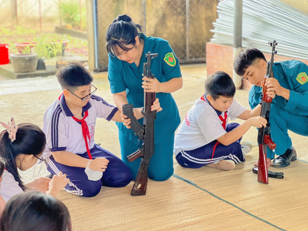 Nữ dân quân Thu Nguyệt cùng đồng đội hướng dẫn học sinh tháo lắp súng trong chương trình “Một ngày làm chiến sĩ” do Nguyệt đề xuất và thiết kế - Ảnh do nhân vật cung cấp