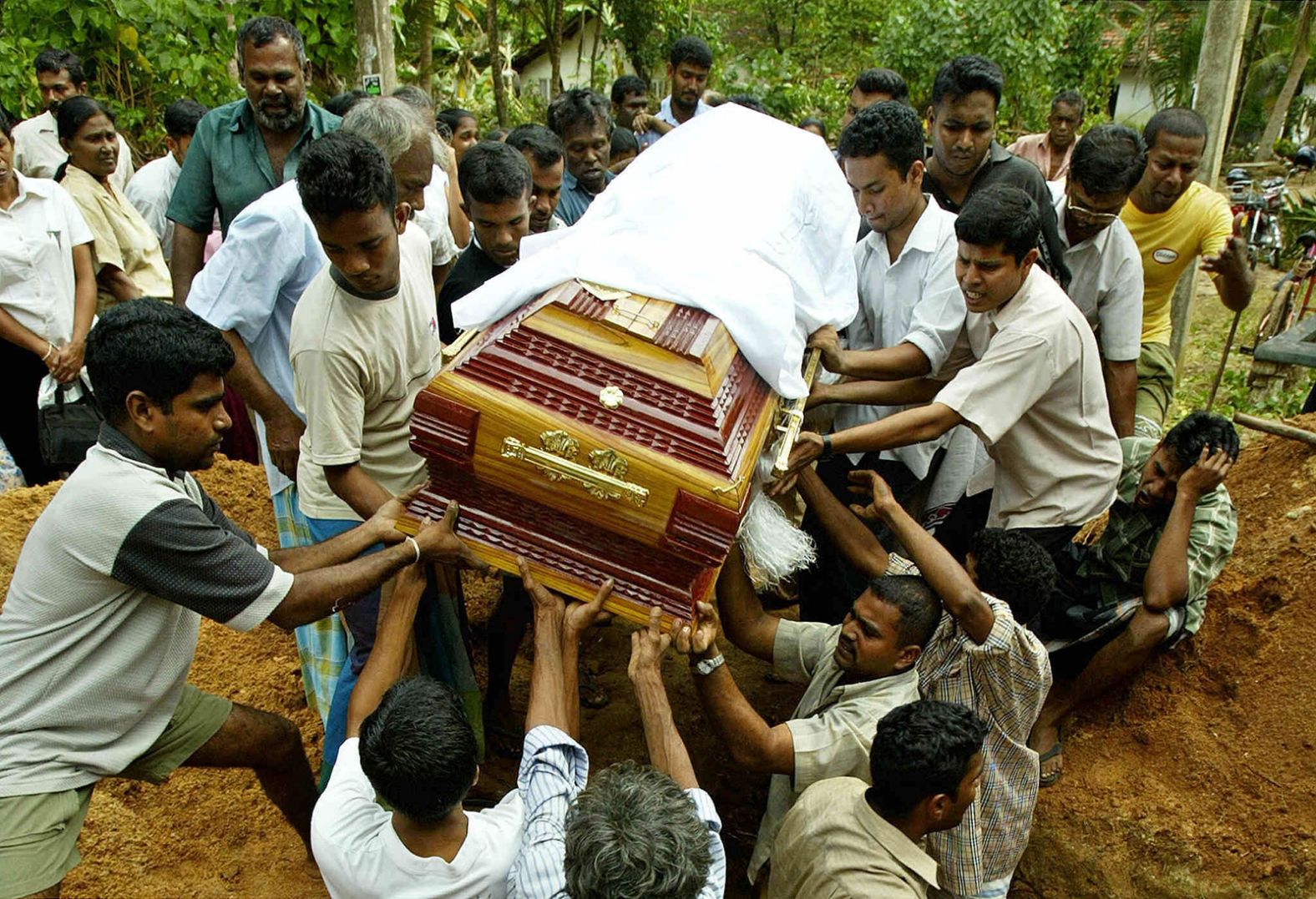 Mọi người hạ quan tài xuống đất trong lễ tang của hai nạn nhân sóng thần ở Matara, Sri Lanka. Jimin Lai/AFP/Hình ảnh Getty