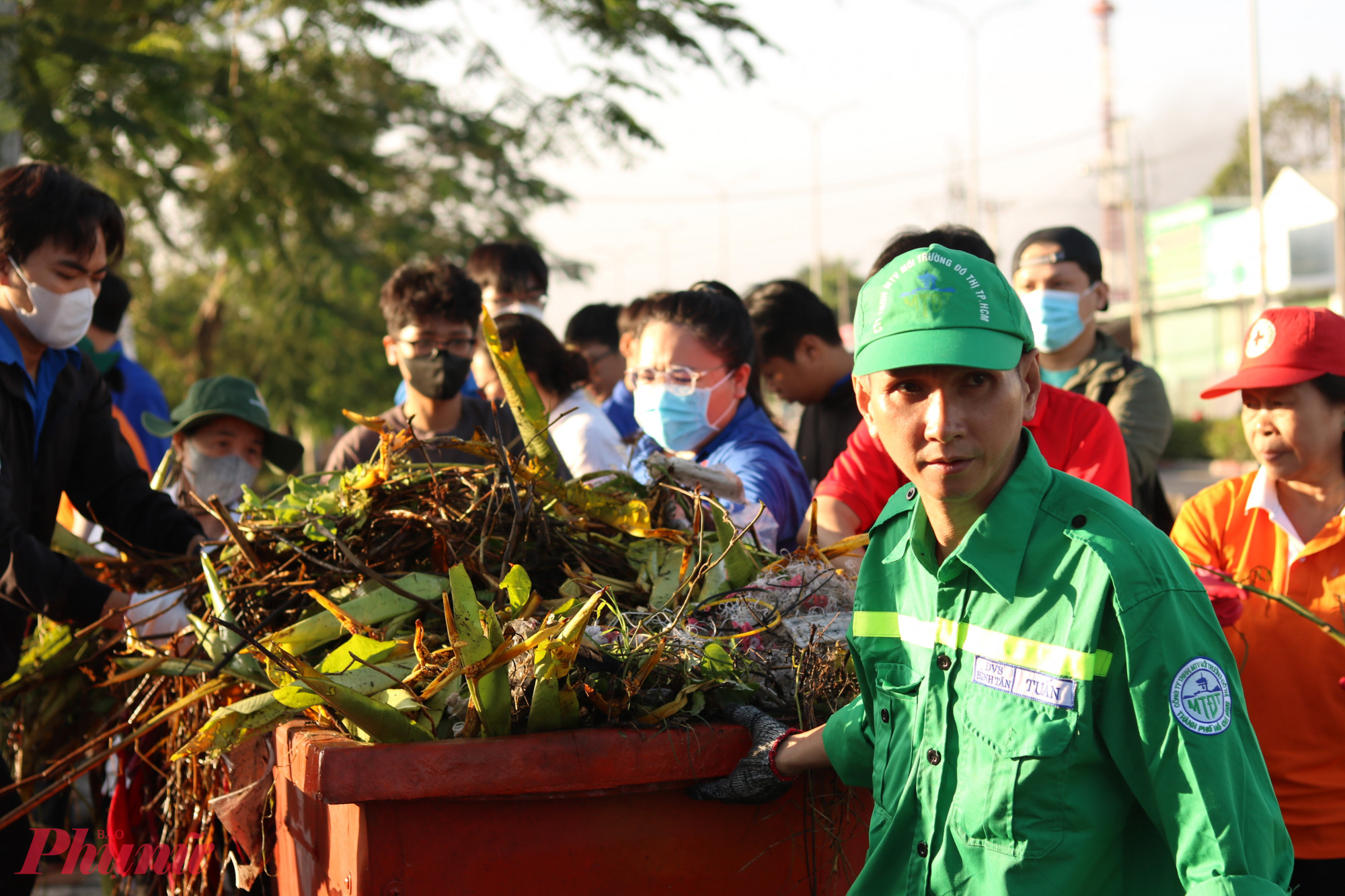 Rác sinh hoạt, cây cỏ dại ven đường được thu gom và nhân viên vệ sinh kéo đến xe xử lý rác. 