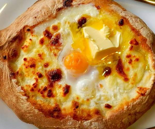 Một trong những loại khachapuri phổ biến nhất, adjarian (ADJARA, Georgia) là một loại bánh nướng hở mặt có nhân là sự kết hợp của phô mai và trứng. Phần đế được làm từ bột men được cán thành hình thuôn dài và theo truyền thống được nhồi bằng phô mai Sulguni hoặc Imeretian , hoặc sự kết hợp của cả hai.  Món ăn được hoàn thiện bằng một quả trứng đặt lên trên, và sau đó bánh được nướng thêm cho đến khi trứng đông lại một phần. Chiếc bánh hình thuyền này có nguồn gốc từ vùng ven biển Adjaria, và thường được phục vụ với một lát bơ ở trên.