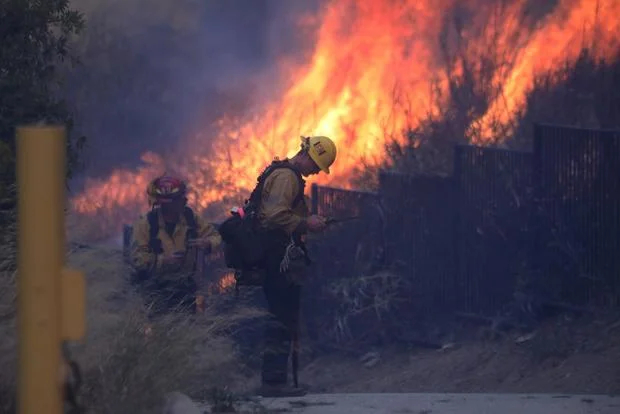 Lính cứu hỏa nỗ lực dập tắt đám cháy gần những ngôi nhà ở Pacific Palisades, California - Ảnh: DAVID SWANSON/AFP