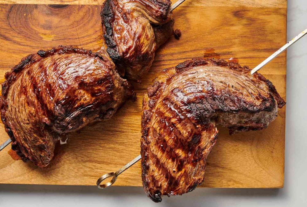 Picanha là một loại thịt bò nổi tiếng trong ẩm thực Brazil, được cắt từ phần mông trên (rump cap) của con bò. Miếng thịt này có lớp mỡ dày bên trên, giúp giữ cho thịt mềm, ngọt và thơm khi nướng. Picanha thường được chế biến bằng cách cắt thành lát lớn, ướp muối và nướng trên than củi hoặc xiên quay. 