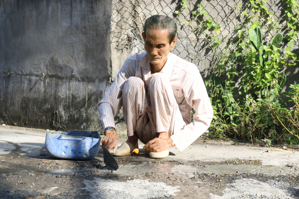 Ông Nguyễn Văn Hừng âm thầm dặm vá đường suốt 8 năm qua tại các xã thuộc huyện Bình Chánh, TPHCM - ẢNH: NGỌC TRĂM