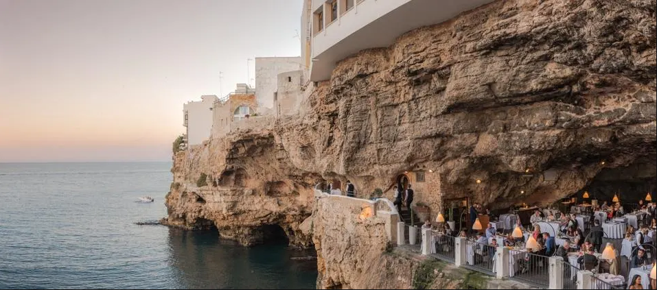 Ăn tối trong hang động ở Ý: Grotta Palazzese là một hang động đá vôi ven biển nhìn ra biển Adriatic ở Polignano Mare, Ý. Trong hang có nhà hàng Ristorante Grotta Palazzese và phải đặt bàn trước hàng tháng. Nhà hàng này nổi tiếng với các món hải sản đi kèm với rượu vang từ vùng Puglia của Ý. Ảnh trên: Grotta Palazzese ở Polignano a Mare, Ý- Ảnh: Getty