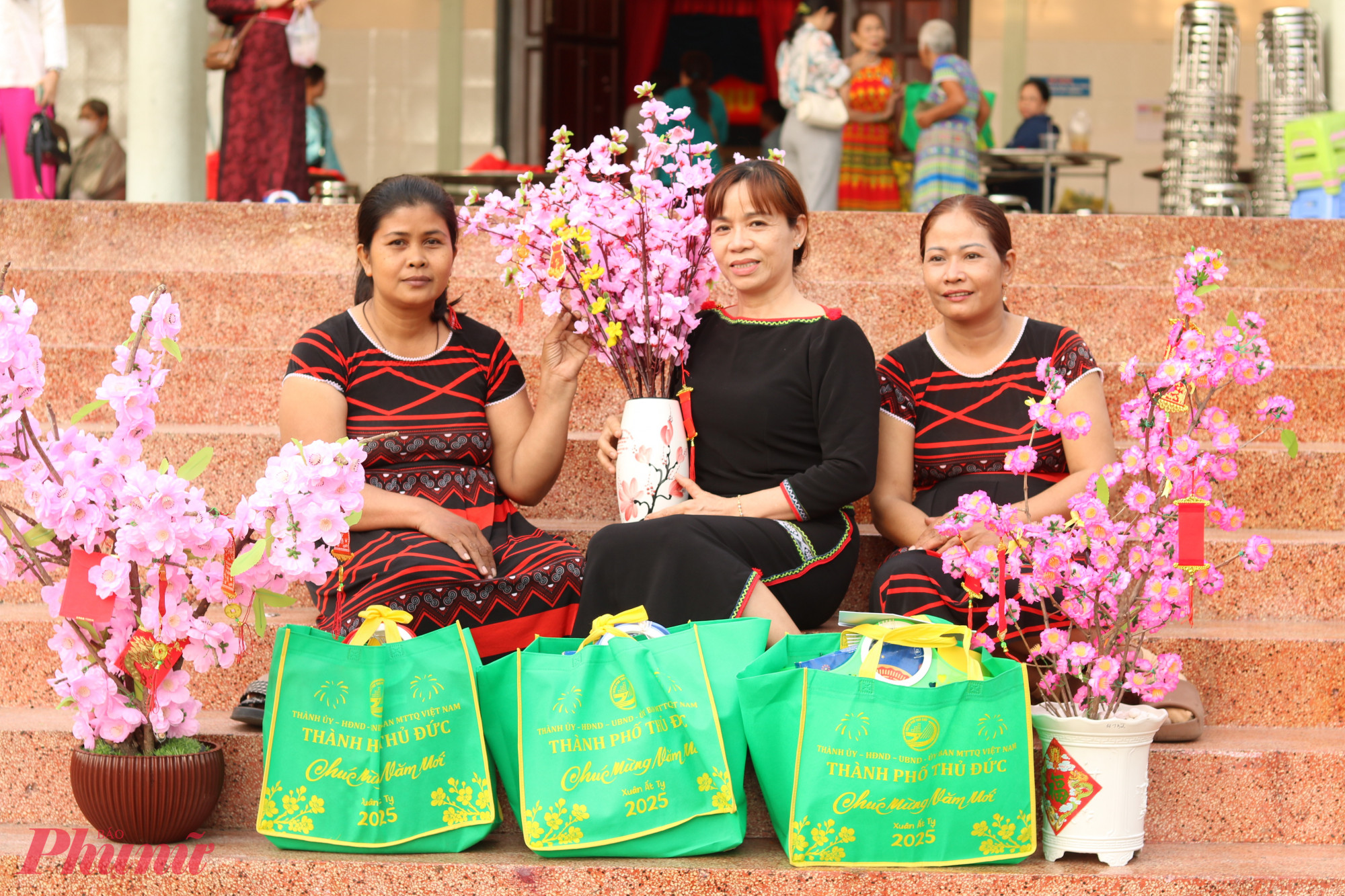 Chị Thạch Thị Bích Hồng (bìa trái) cùng 2 chị bạn ở phường Trường Thọ rất phấn khởi trước món quà vừa được nhận. Chị cho biết gia đình đang ở trọ, kinh tế khó khăn nên chưa năm nào mua sắm gì vào dịp tết. Chở chậu hoa đào này về, chị tin không khí trong căn phòng trọ sẽ ấm hơn, vui hơn.  