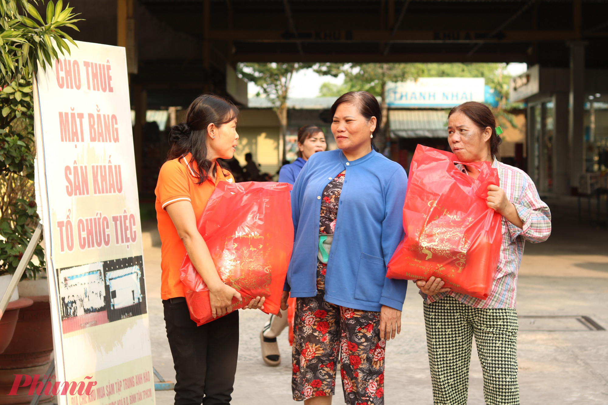 Cánh tay và lưng đau nên bà Nguyễn Thi Cam (giữa) được cán bộ hội ôm giúp túi quà về. Chồng mất sớm, bà làm thuê ở quán ăn, sau đó đi bán khoai lang luộc để có tiền nuôi 2 con ăn học. Bà cho biết vừa được 1 đơn vị quân đội tặng hoa và ít bánh mứt, thêm quà của hội nữa là cả nhà có tết ấm. 