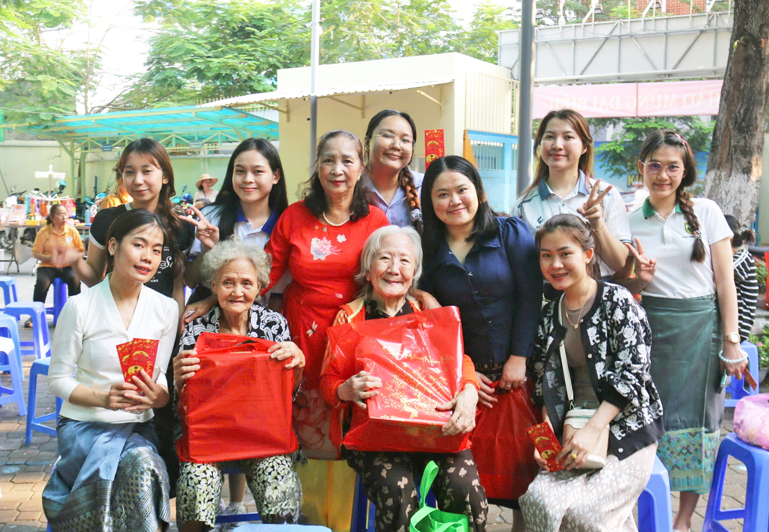 Các sinh viên Lào cùng má Huệ (đứng, thứ ba từ trái sang) trao quà tết cho phụ nữ khó khăn