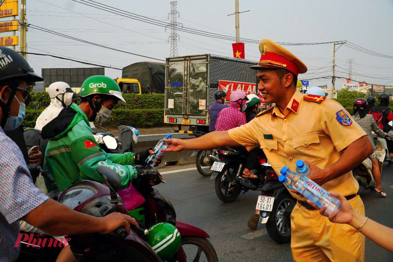 Cảnh sát giao thông TPHCM phát nước suối cho người dân trong chiều ngày 24/1 - Ảnh: PC08 cung cấp