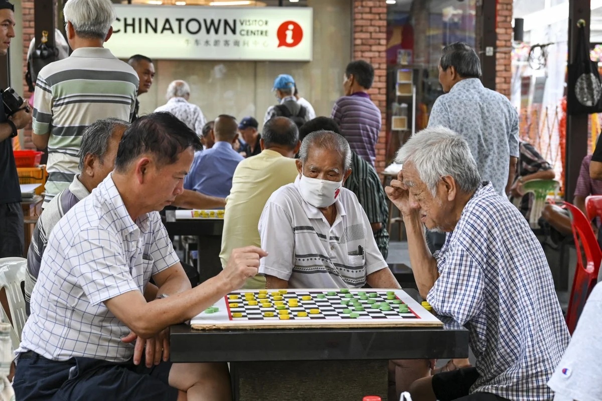 Những người đàn ông lớn tuổi chơi cờ ở khu Chinatown, Singapore - Ảnh: AFP