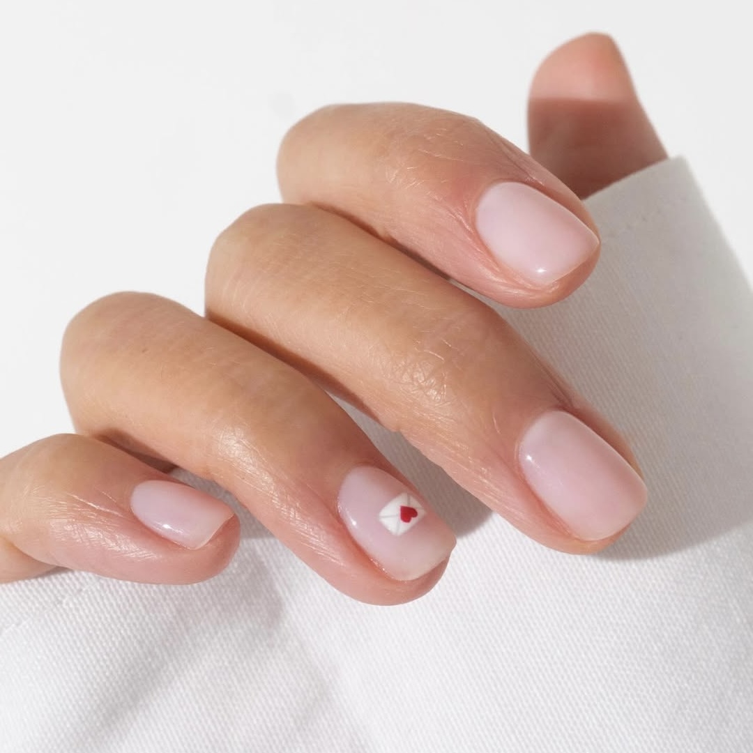  Mẫu nail Valentine màu sơn gạo đơn giản: Móng ngắn sơn màu gạo đơn giản mang đến vẻ đẹp nhẹ nhàng, tinh tế, phù hợp với những ai yêu thích sự thanh thoát. Kiểu móng này sẽ mang lại sự dễ chịu nếu bạn đang thấy “choáng ngợp” trước những mẫu nail Valentine với những gam màu quá rực rỡ. Nếu bạn lo sợ cách sơn móng tay này hơi tẻ nhạt, hình vẽ lá thư tình nhỏ nhắn ở ngón áp út sẽ là điểm nhấn hoàn hảo vừa đủ. 