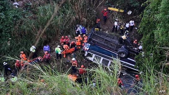 Lính cứu hỏa và cảnh sát làm việc tại hiện trường vụ tai nạn xe buýt ở Guatemala - Ảnh: AFP