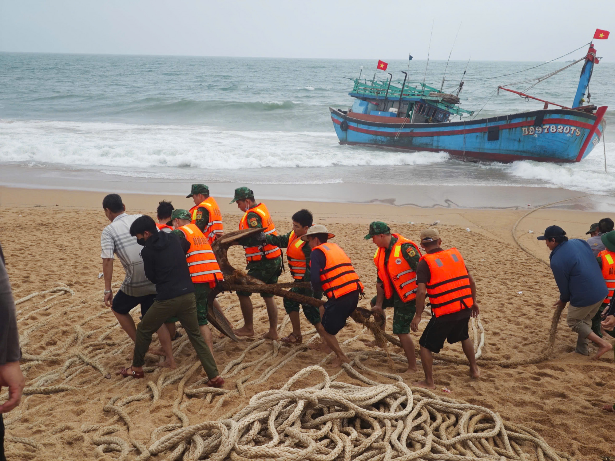 Cán bộ chiến sĩ đồn Biên phòng Hòa Hiệp Nam vớt các vật dụng trên tàu vào bờ.