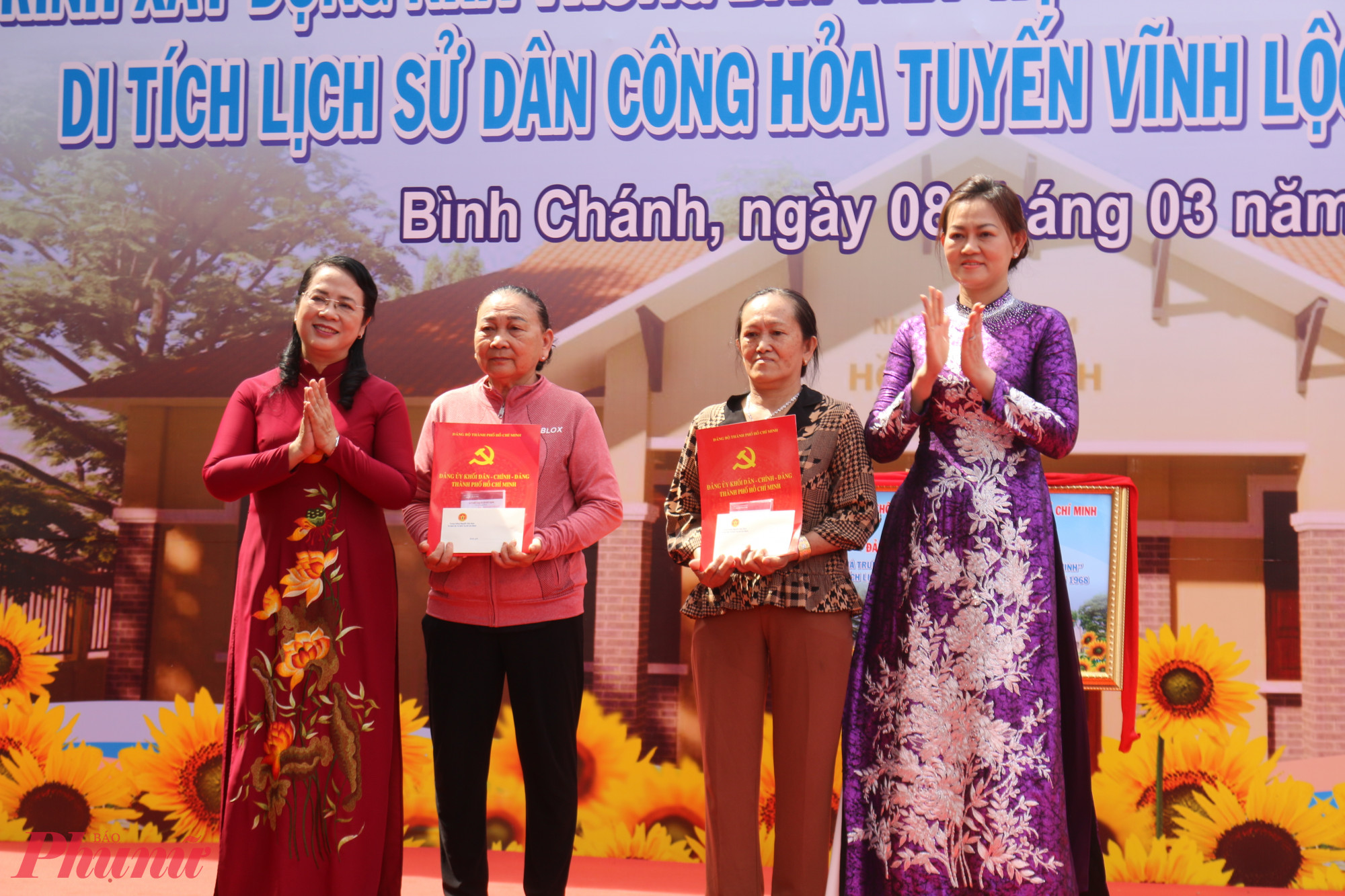 Bà Trần Kim Yến -  Chủ nhiệm Ủy ban Kiểm tra Thành ủy TPHCM (bìa trái) và bà Trần Mộng Điệp - Phu nhân Trung tướng Nguyễn Văn Nam trao sổ tiết kiệm cho thân nhân gia đình các Mẹ Việt Nam Anh hùng