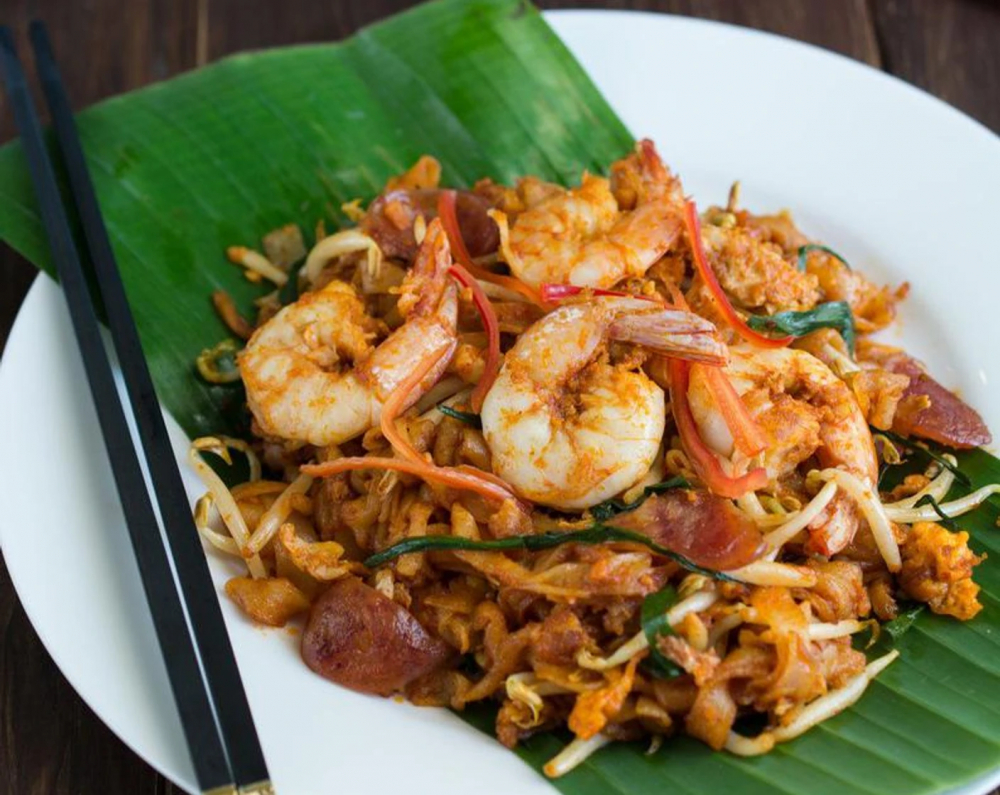 Char Kway Teow là một món mì xào nổi tiếng trong ẩm thực Malaysia và Singapore, đặc biệt phổ biến ở các khu vực của Penang. Món này bao gồm sợi mì phẳng (kway teow) được xào nhanh trên lửa lớn với các nguyên liệu như tôm, sò, thịt heo, trứng, giá đỗ, và đôi khi có cả chả lụa hoặc thịt gà. Nước sốt xào được làm từ sự kết hợp của dầu hào, tương đen, tỏi, và đôi khi có chút tương ớt, mang đến hương vị đậm đà, ngọt ngào, và cay nồng.  Điểm đặc biệt của Char Kway Teow là việc xào mì trên chảo lớn (wok) với nhiệt độ cao, tạo nên một hương vị charred đặc trưng, giúp các nguyên liệu thấm đều gia vị và giữ được độ giòn nhẹ từ các thành phần như tôm hoặc giá đỗ. 