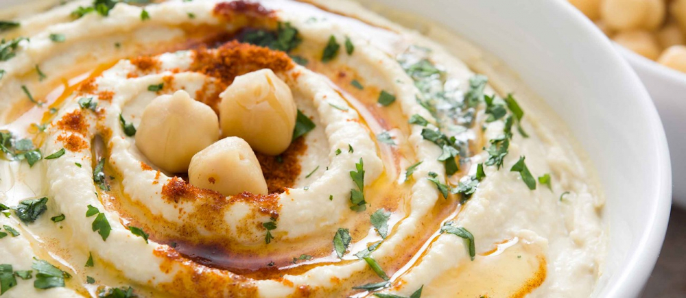 Hummus là một món ăn chay nổi tiếng ở Trung Đông, được làm chủ yếu từ đậu gà (hoặc đậu xanh) nghiền nhuyễn, trộn với tahini (mè xay), tỏi, nước chanh, dầu ô liu và gia vị như cumin, muối, tiêu. Món này có vị béo ngậy từ tahini, thanh mát từ chanh và chút cay nhẹ từ tỏi. Hummus rất giàu protein, chất xơ, và chất béo lành mạnh, giúp cung cấp năng lượng lâu dài, hỗ trợ tiêu hóa và tốt cho tim mạch. Nó thường được ăn kèm với bánh pita, rau sống hoặc như một món chấm.