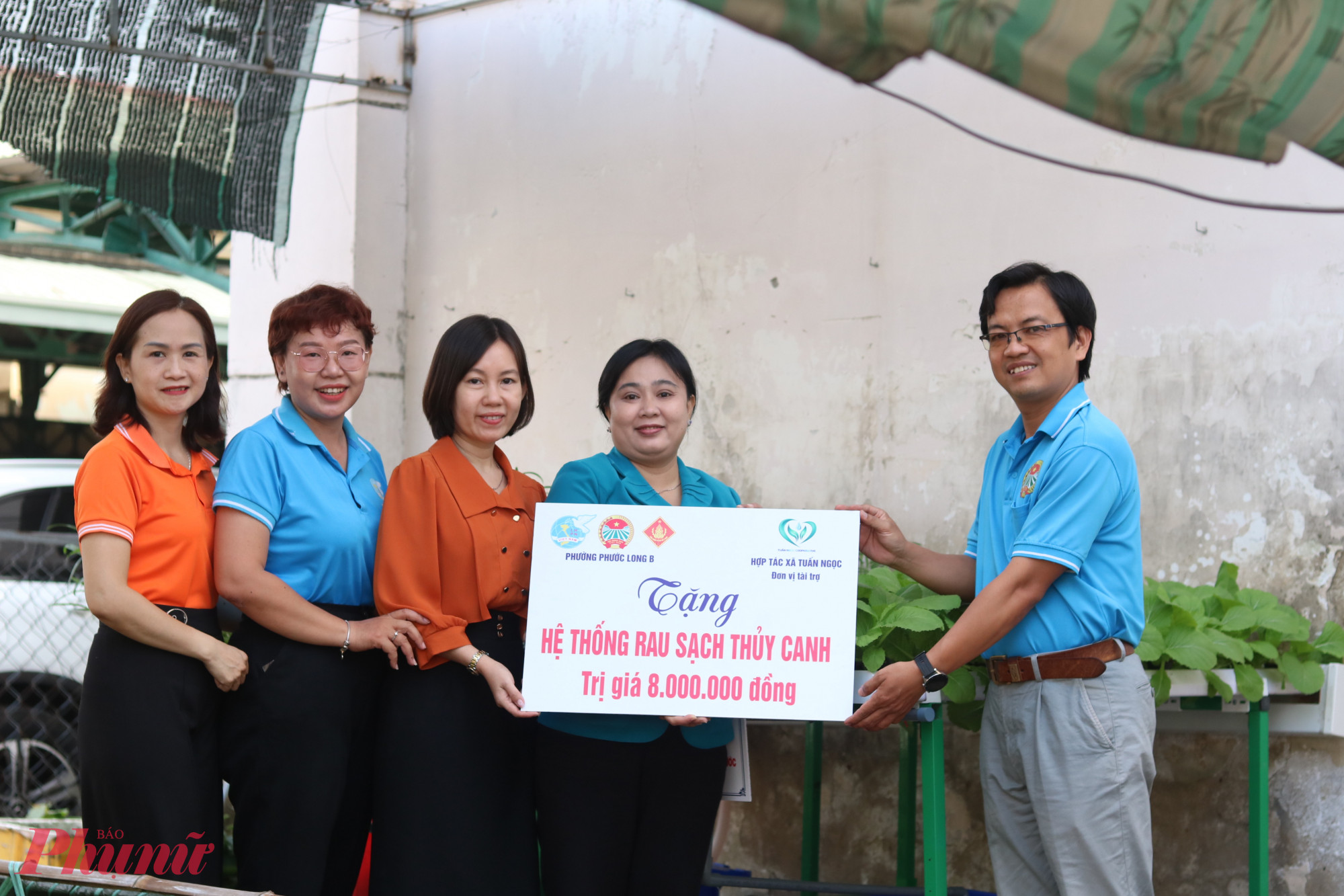 Anh Lâm Ngọc Tuấn – Giám đốc Hợp tác xã nông nghiệp Tuấn Ngọc – trao bảng tượng trưng cùng hệ thống rau sạch thuỷ canh cho đại diện đoàn thể phường Phước Long B. 