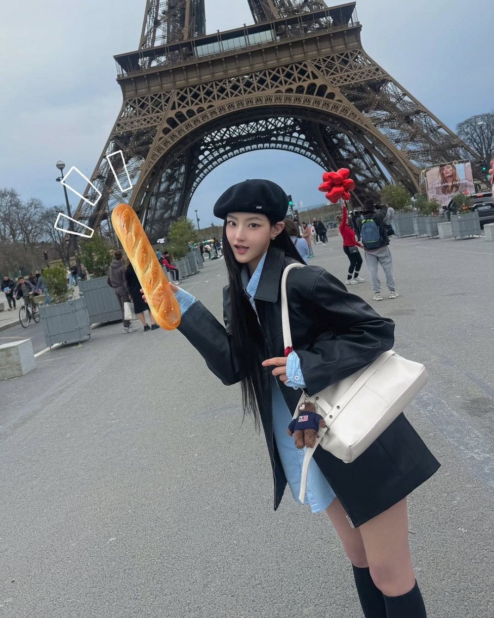 Giữa những con phố cổ kính của Paris, Haneul vẫn giữ vững phong cách riêng khi khéo léo biến chiếc móc khóa gấu bông Steve Heritage từ Who.A.U (19.900 KRW) thành điểm nhấn dễ thương trên chiếc túi của mình. Diện áo sơ mi dáng váy cùng áo khóac nhẹ và chiếc mũ beret xinh xắn, cô nàng mang đến một vibe Paris nhẹ nhàng, cổ điển nhưng vẫn căng tràn vẻ tươi mới. Và chính chiếc móc khóa gấu bông mang đến tổng thể đối lập đầy thú vị, một nét chấm phá dễ thương, khiến bộ trang phục thêm phần sống động và gần gũi hơn. Nhỏ xíu nhưng nổi bật, chiếc móc khóa này  đầy tiềm năng “gây nghiện” cho những ai yêu thích phụ kiện mang dấu ấn cá nhân.