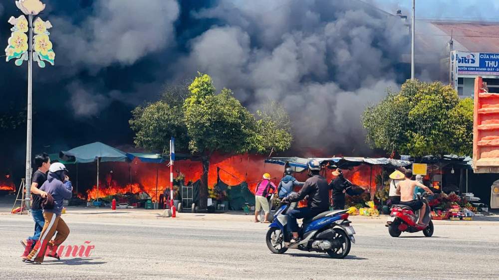 Ngọn lửa bao trùm, cột khói bốc cao. Một số hộ kinh doanh trái cây, xe đạp điện và một số mặt hàng khác bên ngoài chợ hô hoán ứng cứu và khẩn cấp di chuyển đồ đạc ra xa đám cháy.