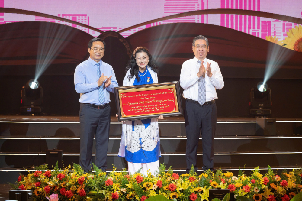 Chủ tịch UBND TPHCM Nguyễn Văn Được và Chủ tịch Ủy ban MTTQ Việt Nam TPHCM Nguyễn Phước Lộc trao bảng vàng tri ân cho NSND Kim Cương - Ảnh: Trang Nguyễn